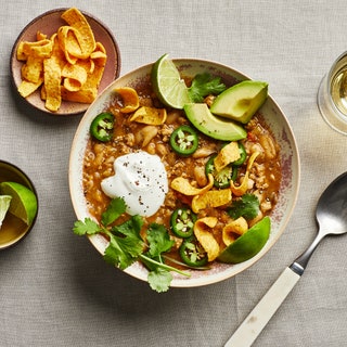 Bowl of white chicken chili topped with Fritos cilantro jalapeño avocado and sour cream.