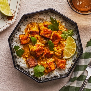 Baked Tofu Satay over Rice in a black bowl on a white fabric