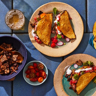 A spread of spiced mushroom tacos with toppings including lime wedges cilantro charred tortillas and more.